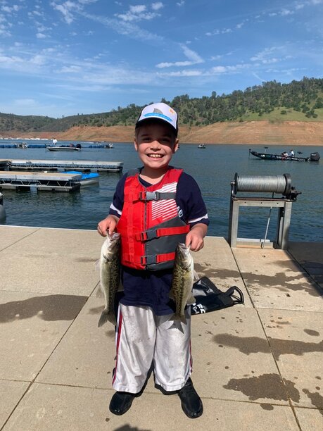 This youth angler is all smiles as he holds up two nice spotted bass from the recent Lake McClure event